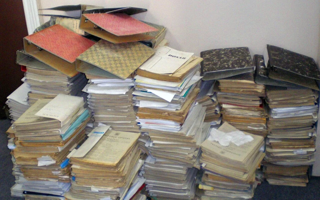 Pile de dossiers et formulaires administratifs illustrant le poids de la paperasserie bureaucratique
